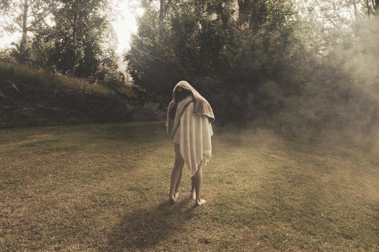 A figure draped in cloth on a misty lawn